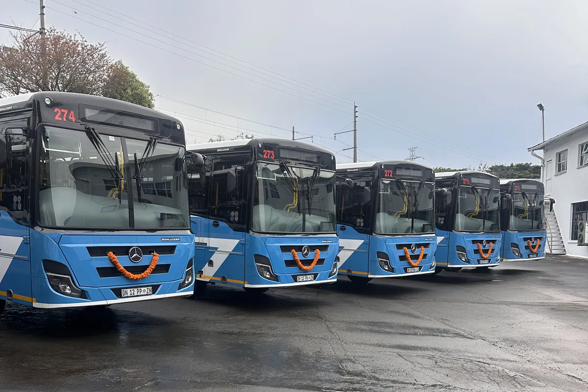 New blue and white Dass buses parked in a row at the depot, with marigold garlands on their grilles